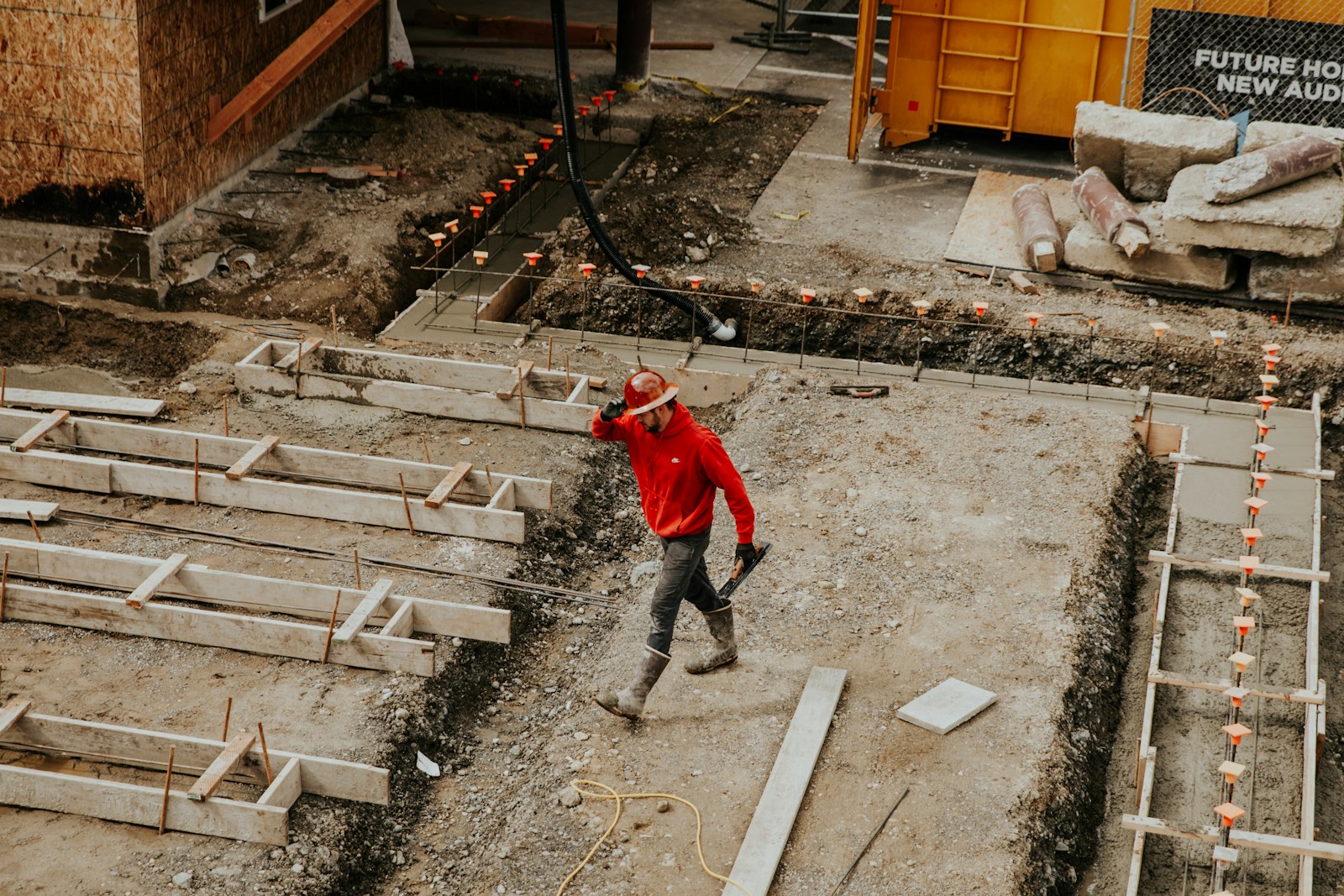 man in red jacket and black pants with contractors insurance walking on gray concrete stairs