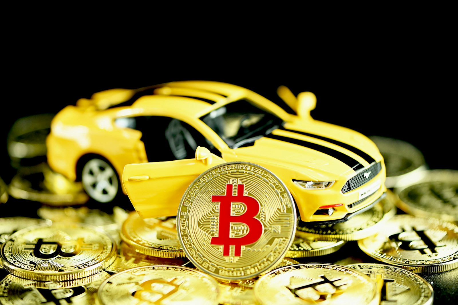 a yellow toy car sitting on top of a pile of gold coins symbolizing auto insurance rates